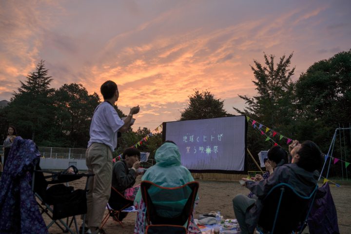 夕暮れの校庭で映画が上映されている「地球とヒトが笑う映画祭」の様子