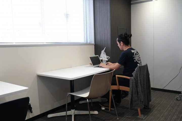 コワーキングスペースにてノートパソコンでで仕事に取り組む男性
